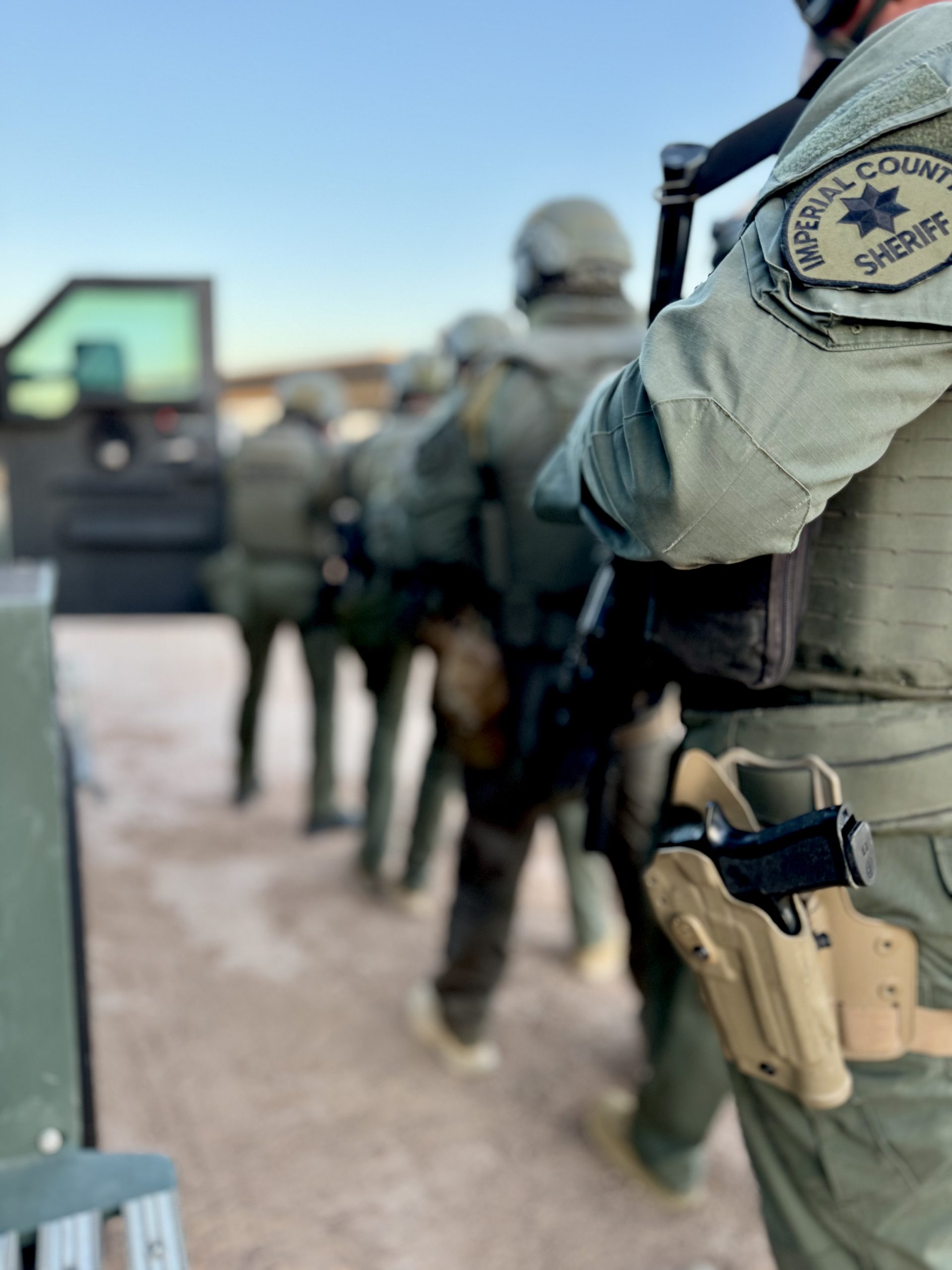 Imperial County Sheriff's Emergency Response Team members in tactical gear during a firearms training exercise, wearing helmets, body armor with the Imperial County Sheriff patch, and sidearms holstered